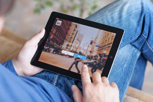 A person taps on an iPad that is open to LinkedIn