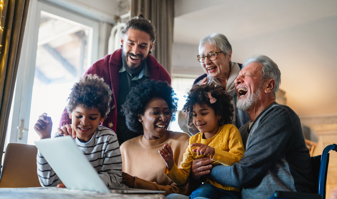A happy multi-generational family laughing together at home. Pictured are two children and four adults.